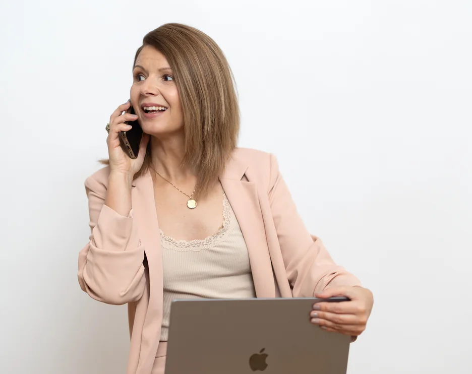 Jacqueline Pröll telefoniert lachend und hält ihren Laptop am Schoß