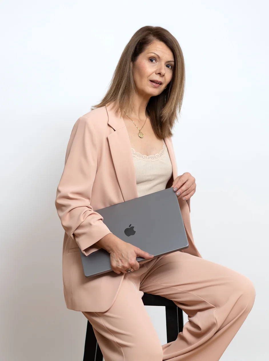 Jacqueline Pröll sitzt mit ihrem Laptop auf einem Hocker im Studio